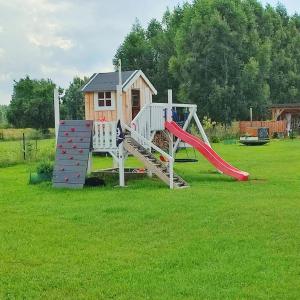 un parque infantil con tobogán y una casa de juegos en PUSZCZYKOWO siedlisko&spa, en Białowieża