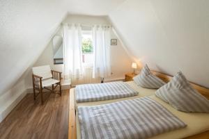 2 Betten in einem Dachzimmer mit Fenster in der Unterkunft Ferienhaus Seestern in Dornumersiel
