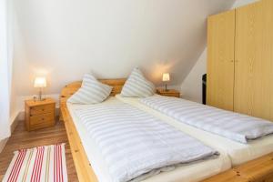 ein großes Bett mit zwei Kissen darauf in einem Zimmer in der Unterkunft Ferienhaus Seestern in Dornumersiel