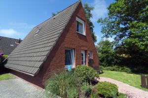 ein kleines Backsteinhaus mit einem Walmdach in der Unterkunft Ferienhaus Seestern in Dornumersiel