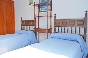 2 Betten in einem Schlafzimmer mit blauer Bettwäsche in der Unterkunft Apartamento El Corro: con parking en pleno centro de Comillas in Comillas