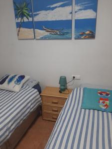 a bedroom with two beds and a nightstand and paintings on the wall at Nice apartment with spacious terrass and rooftop in Los Alcázares