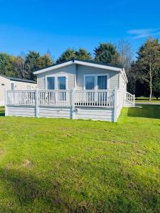 a white house with a porch on a grass field at Hemingway Lodge with Hot Tub in York