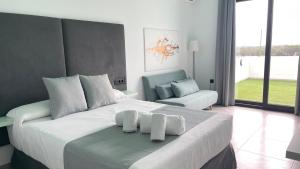 um quarto com uma grande cama branca e uma cadeira em ON The Residence em Matalascañas