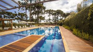 a large swimming pool with a wooden walkway next to a resort at Hotel Toriba in Campos do Jordão