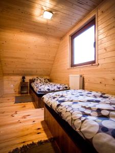 2 łóżka w drewnianym pokoju z oknem w obiekcie Domki nad Wartą w mieście Prusicko
