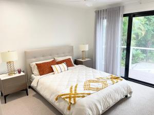 a white bedroom with a large bed and a window at Unbeatable Riverfront Luxury Resort Style House in Gold Coast