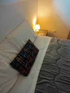 białe łóżko z poduszką i lampą w obiekcie Bologna House Fiera w Bolonii