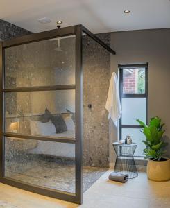 a bathroom with a glass shower with a bed in it at Menlyn Boutique Hotel in Pretoria