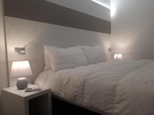 1 dormitorio con cama blanca y mesa con lámpara en Antichi Sapori Apartment One, en Bellagio