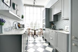 a kitchen with white cabinets and a checkered floor at 16 Lansdown Flat 3 - By Luxury Apartments in Cheltenham