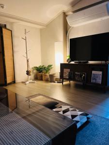 uma sala de estar com uma televisão de ecrã plano na parede em Jeju Time em Jeju