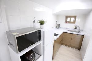 a white kitchen with a sink and a microwave at Jeju Time in Jeju