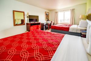 a hotel room with two beds and a red blanket at Rodeway Inn Central Colorado Springs in Colorado Springs