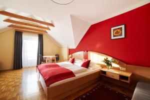バート・ブルーマウにあるHotel Garni Thermenoaseの赤い壁のベッドルーム(ベッド1台、テーブル付)