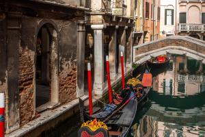 two gondolas are parked in a canal in a city at Al Gazzettino in Venice