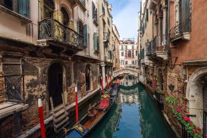 um canal entre dois edifícios com barcos em Al Gazzettino em Veneza