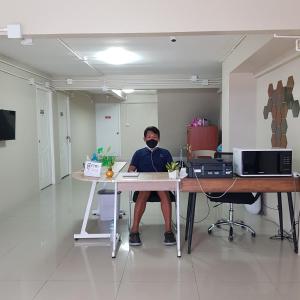 a man sitting at a desk wearing a mask at Checkin Hostel @DonMuang Airport in Bangkok