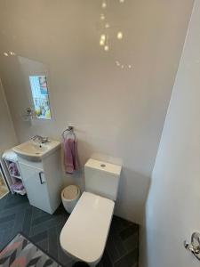 a white bathroom with a toilet and a sink at Beach retreat in Prestatyn