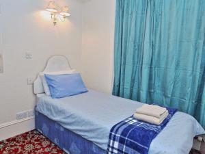 a small bedroom with a bed with blue curtains at Brentwood Villa Bed and Breakfast in Aberdeen