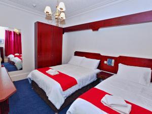 um quarto com 2 camas com lençóis vermelhos e brancos em Brentwood Villa Bed and Breakfast em Aberdeen