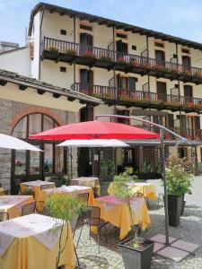 un ristorante con tavoli e ombrelloni di fronte a un edificio di Albergo Miniere a Traversella