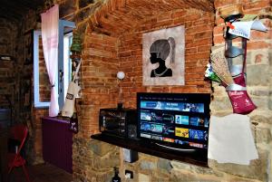 a room with a brick wall with a tv on it at NIDO SCANSANESE in Scansano