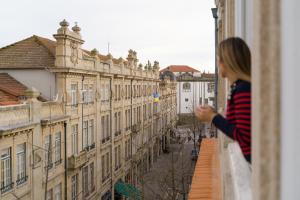 a woman looking out from a balcony of a building at Galerias Nightlife Fashion Flats in Porto +36 photos