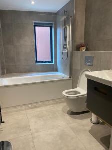 a bathroom with a tub and a toilet and a window at Icona - Stylish 2 bed apartment in York