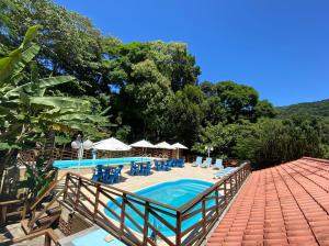a pool with chairs and umbrellas on a patio at Pousada Mata Nativa in Abraão