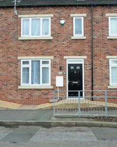 a brick building with a black door in front of it at Entire Modern Home with Private Parking for 6/8 Persons in Worksop