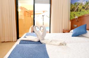 a bedroom with a bed with two swans towels on it at Hotel Portonovo in Portonovo