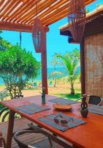 un tavolo in legno su una terrazza con vista sull'oceano di Casa Beira Mar Pitinga a Arraial d'Ajuda