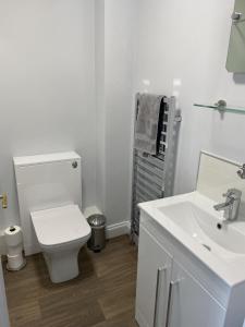 a white bathroom with a toilet and a sink at The Sorting House in Hunstanton