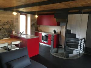 uma cozinha com armários vermelhos e uma mesa e uma cozinha com um fogão em RUSTICO Orabino & SAUNA em Corzoneso