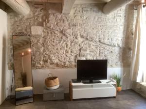 ein Wohnzimmer mit einem TV an einer Steinmauer in der Unterkunft L'Etoile in Nîmes
