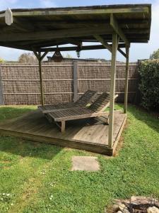 a wooden deck with a bench under a gazebo at Charmant chalet à 400 m de la mer in Guidel