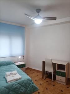 a bedroom with a bed and a desk and a ceiling fan at Apartamentos San Antón 2 in Córdoba