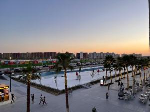 een groep mensen die rond een zwembad met palmbomen lopen bij Amazing view apartment in Golf Porto Marina. in El Alamein