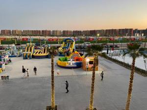 een park met een speeltuin met palmbomen en mensen bij Amazing view apartment in Golf Porto Marina. in El Alamein