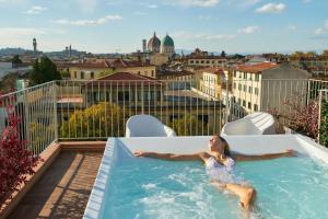 Eine Frau entspannt sich in einem Whirlpool auf einem Dach. in der Unterkunft Forte16 View & SPA in Florenz