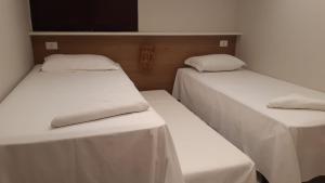 two beds in a room with white sheets at Costa Dourada Village in Maragogi