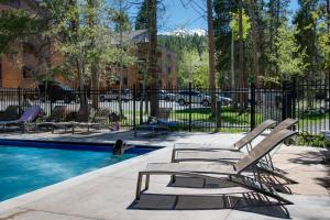 a pool with lounge chairs and a black fence at Inner Circle 15 Serenity Condo Great Breck Location in Breckenridge
