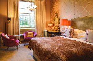 a hotel room with a large bed and a window at Bishopstrow Hotel and Spa - Small Luxury Hotels of the World in Warminster