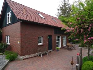 ein rotes Backsteinhaus mit einer Backsteinterrasse in der Unterkunft Ferienhaus 258 S in Eckwarden in Eckwarden