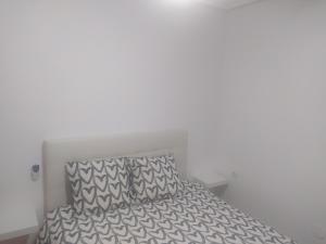 a bed with a gray and white bedspread and a pillow at APARTAMENTO Daniel in Benalmádena