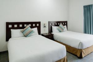 two beds in a hotel room with white sheets at Almarea Vacation Condo in Playa del Carmen