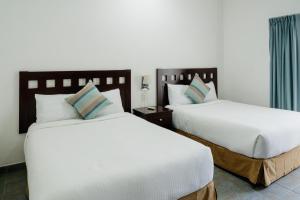 two beds in a hotel room with white sheets at Almarea Vacation Condo in Playa del Carmen +114 photos