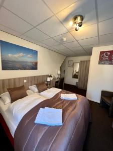 une chambre d'hôtel avec un grand lit et des serviettes. dans l'établissement SEA YOU Hotel Noordwijk, à Noordwijk aan Zee