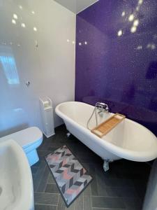 a bathroom with a white tub and a purple wall at Beach retreat in Prestatyn
